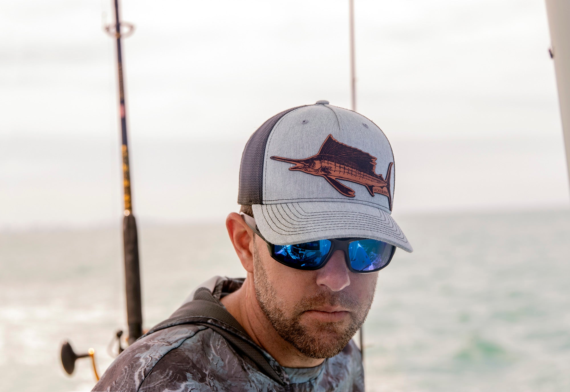 a photo showcasing a Richardson 112 snap-back trucker fishing hat with a Mokie Burns™ leather patch depicting an Atlantic Sailfish, perfect for recreational saltwater fishermen and those interested in offshore fishing accessories and hats.